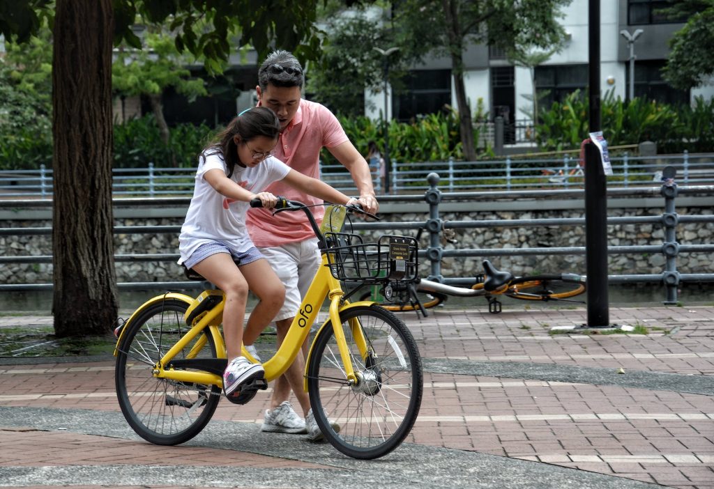 a girl riding a bike with the help of her father